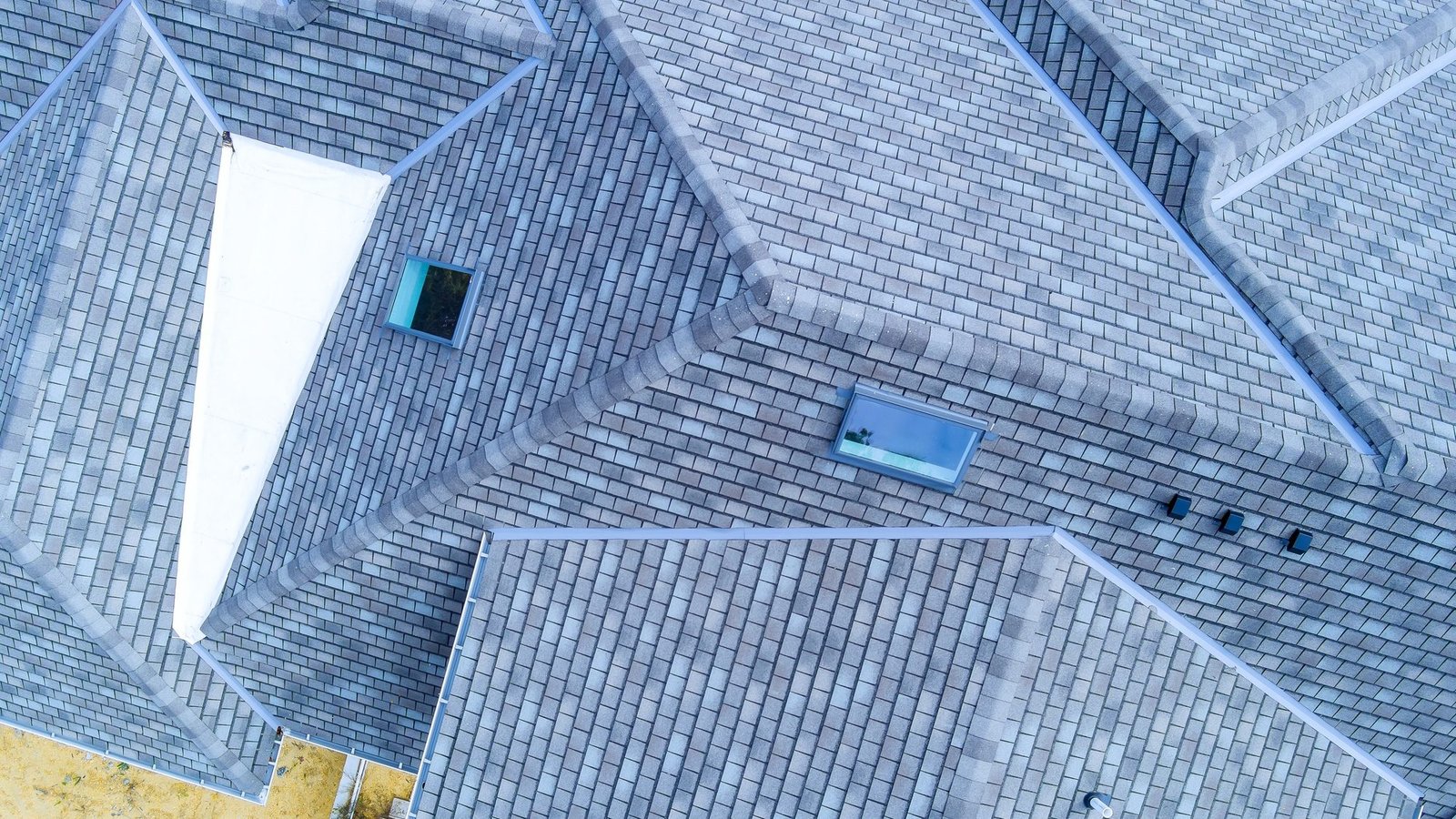 Construction roof of new house is being covered with asphalt shingles while building